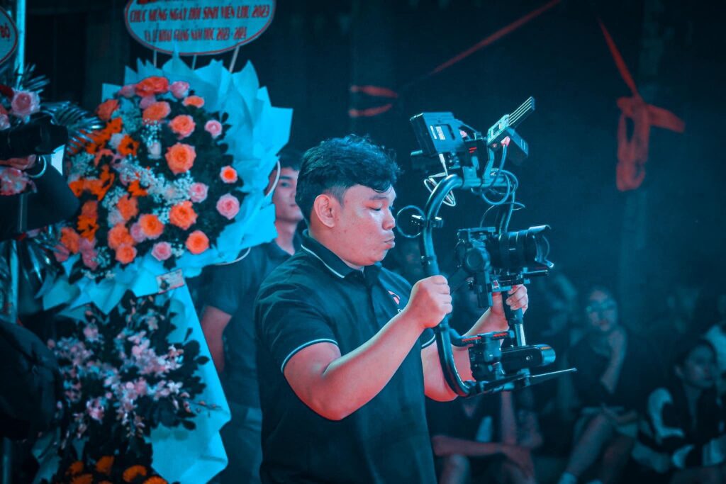 Cameraman đang tập trung quay phim sự kiện tại một hội nghị lớn, bắt trọn khoảnh khắc khán giả vỗ tay